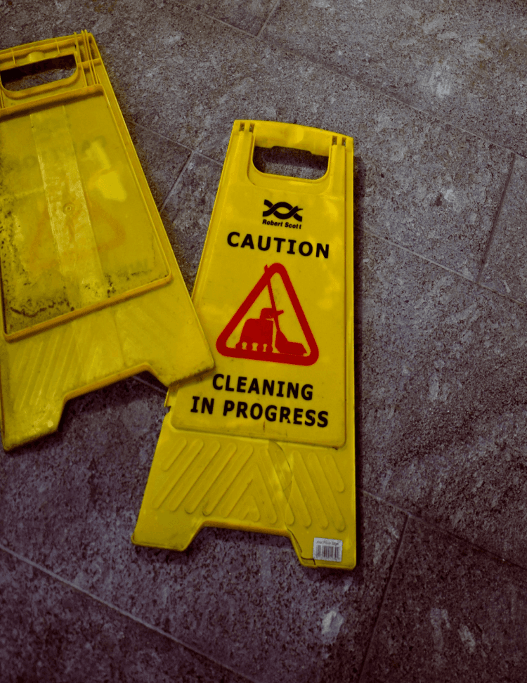 Close up of a yellow warning sign on the floor saying 'cleaning in progress'.